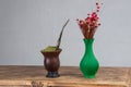 Chimarrao cuia next to a flower vase on top of a wooden table Royalty Free Stock Photo