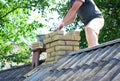 Chimney construction and re-building. A contractor is building a chimney on an asbestos roof