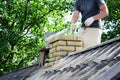 Chimney construction, repairs and re-building. A contractor is bricklaying a brick chimney on an house asbestos roof Royalty Free Stock Photo