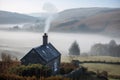 the chimney of a cottage surrounded by the misty fog, against a backdrop of rolling hills Royalty Free Stock Photo