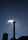 Chimney exhausting steam in blue sky