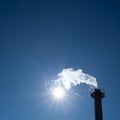 Chimney exhausting steam in blue sky