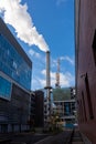 Chimney of a factory emitting dense white smoke in a street of an industrial area