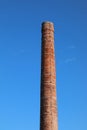 chimney made with exposed bricks of a buttock factory and the blue sky in the background