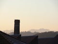 Chimney of old abandoned industrial complex. Work of industrial archaeology. In the background the profile of the mountains Alps Royalty Free Stock Photo