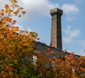 Chimney stack on a building, fall coloured leaves on trees