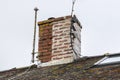 Chimney stack on a house roof, partly weather sealed and repaired with a recent repointing of its mortar cement