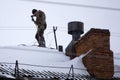 Chimney sweep man in work uniform cleaning chimney on building roof . Royalty Free Stock Photo