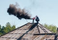 Chimney sweep man in work uniform cleaning chimney on roof Royalty Free Stock Photo