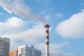 Chimney of a thermal station with a long plume of smoke among residential buildings, ecology