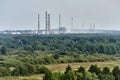 Chimneys of chemical plant polluting air and environment, rise behind forest