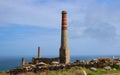 Engine house chimneys at former copper, tin and arsenic mine at Levant with Pendeen lighthouse in background west Cornwall England