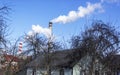 Chimneys of the plant, from which thick white smoke rises into the blue clear sky above the outskirts of the city. Air pollution