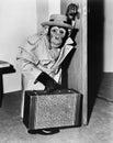 Chimpanzee in coat and hat walking with a suitcase