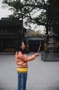 CHINA, SHANGHAI - NOVEMBER 7, 2017: Chinese woman is praying at a Buddhist temple and burning incense sticks Royalty Free Stock Photo