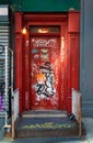 The old red-painted metal door with the graffiti and stickers somewhere in Chinatown of Manhattan. Royalty Free Stock Photo