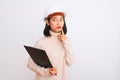 Chinese architect woman wearing helmet holding clipboard over isolated white background serious face thinking about question, very Royalty Free Stock Photo