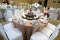 A chinese banquet table setting at a restaurant with white chairs and light pink table