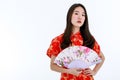 A Chinese beautiful woman with long black hairs in red traditional dress is standing and holding native style paper fan in front Royalty Free Stock Photo