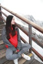 Chinese beauty wears mountain parka sit on stairs on snow mountain