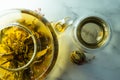 Chinese blooming tea. A glass teapot with a blooming tea flower on a white table. a cup of Chinese blooming tea and tea balls. Royalty Free Stock Photo