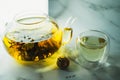 Chinese blooming tea. A glass teapot with a blooming tea flower on a white table. a cup of Chinese blooming tea and tea balls. Royalty Free Stock Photo