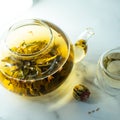 Chinese blooming tea. A glass teapot with a blooming tea flower on a white table. a cup of Chinese blooming tea and tea balls. Royalty Free Stock Photo