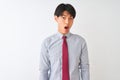 Chinese businessman wearing elegant tie standing over isolated white background In shock face, looking skeptical and sarcastic,