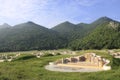 Chinese cemetery on the mound in the meadow next to the mountains.