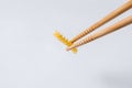 Chinese chopsticks keep in front of pasta girandole on a white background. Ingredient for cooking Royalty Free Stock Photo