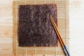 Chinese chopsticks and sushi mat with seaweed background. Royalty Free Stock Photo