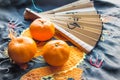 Chinese Christmas decoration-traditional paper fan and tangerines on silk fabric, background with embroidered dragon Royalty Free Stock Photo