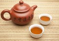 Chinese clay tea pot with two cups of tea on a straw mat. Transl Royalty Free Stock Photo