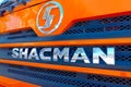 Chinese construction vehicle Shacman brand logo on the orange industrial truck car close up.