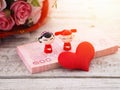 Chinese couple dolls on pile of banknotes and heart shape over blurry flowers bouquet on wooden table