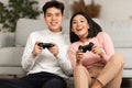 Chinese Couple Playing Video Game Sitting On Sofa Indoors Royalty Free Stock Photo