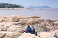 Chinese couple sitting on rocks at the seaside at Mount Luojia, at Lotus Sea to the southeast of Putuo Mountain, Zhoushan,