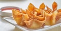 Chinese crab rangoon fried wontons on plate with red sauce