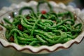 A traditional Chinese dish of green string beans with red chili pepper, served in a white plate. Beijing, China.