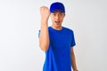 Chinese deliveryman wearing blue t-shirt and cap standing over isolated white background angry and mad raising fist frustrated and