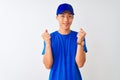 Chinese deliveryman wearing blue t-shirt and cap standing over isolated white background celebrating surprised and amazed for