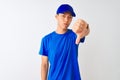 Chinese deliveryman wearing blue t-shirt and cap standing over isolated white background looking unhappy and angry showing