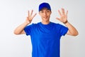 Chinese deliveryman wearing blue t-shirt and cap standing over isolated white background showing and pointing up with fingers