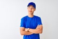 Chinese deliveryman wearing blue t-shirt and cap standing over isolated white background smiling looking to the side and staring
