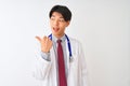 Chinese doctor man wearing coat tie and stethoscope over isolated white background smiling with happy face looking and pointing to Royalty Free Stock Photo