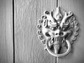 Chinese dragon head door knocker on wooden door. Monochrome photography.