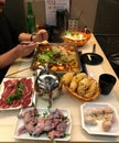 Chinese dumplings, raw meat, raw frog legs on the table, prepared for self-cooking on an induction stove in broth in a Chinese caf