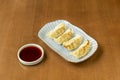 Chinese dumplings stuffed with vegetables cooked on the grill on a plate decorated with blue lines and a small container with soy