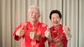 Chinese elderly senior couple in red costume thumb up gesture