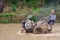 Chinese farmer working in rice field with a motorized plow